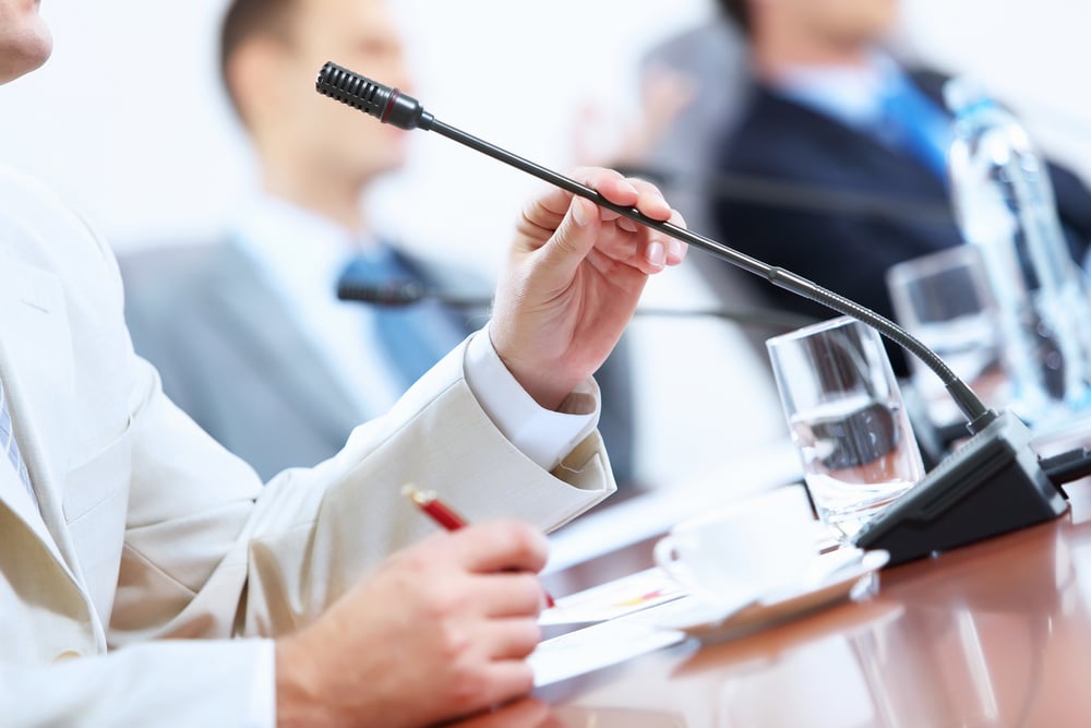 Image of businessmans hands holding microphone at conference